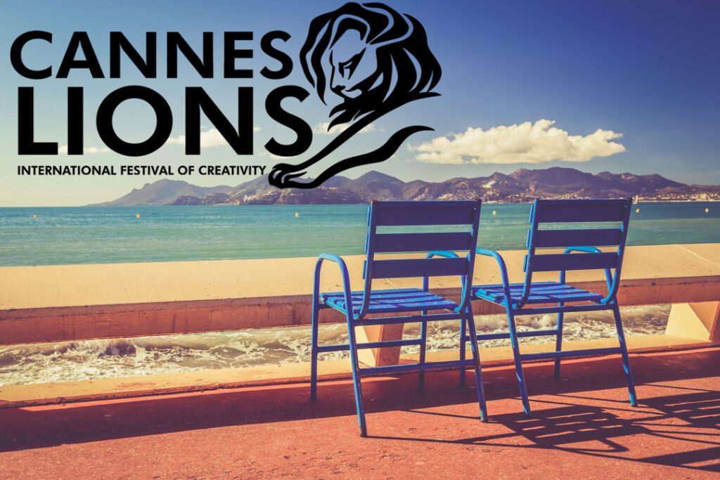 Cannes Lions International Festival of Creativity logo with iconic lion emblem overlooking the Mediterranean coastline from Cannes, featuring two blue director's chairs on a terrace with mountains in the background