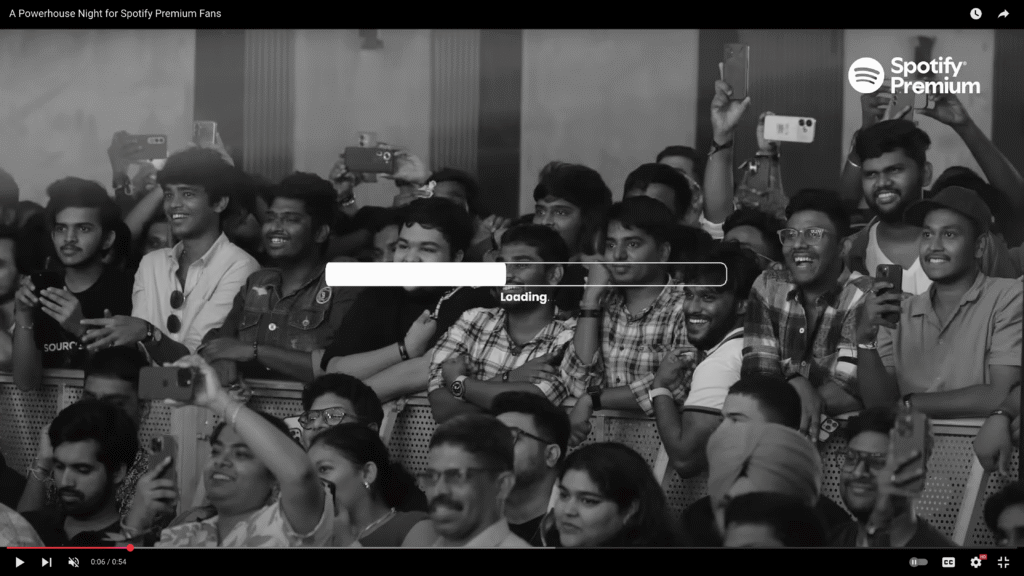 Audience members at a Spotify Premium event in black and white, eagerly watching and recording the live performance from the front rows.