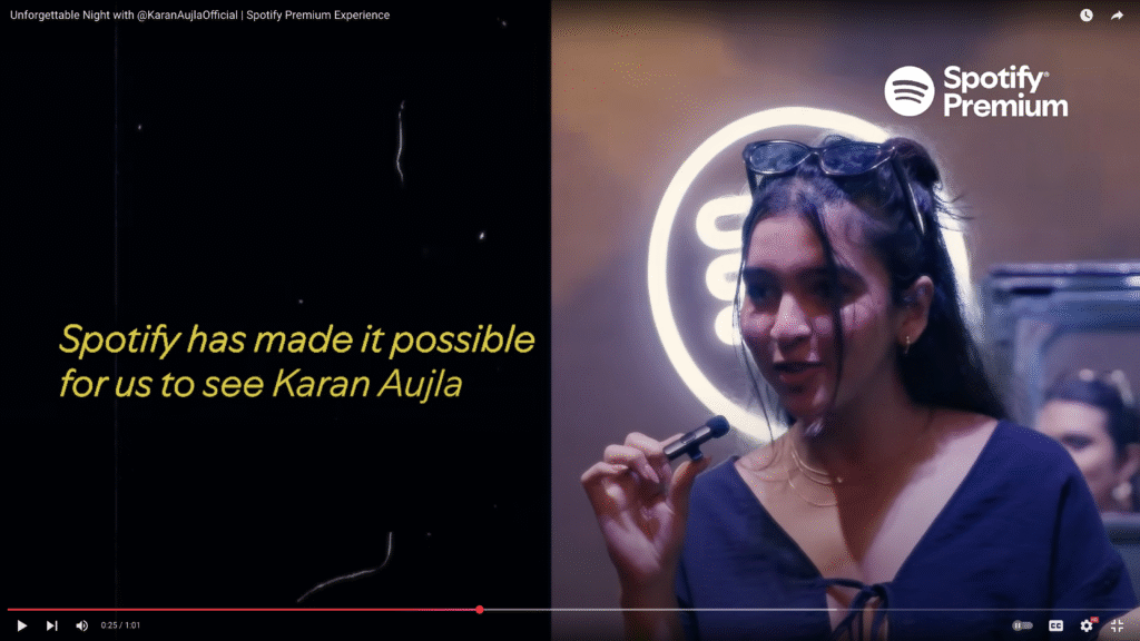 A fan expresses gratitude for Spotify Premium, holding a microphone in front of the Spotify logo, with an onscreen quote about seeing Karan Aujla during an exclusive event.