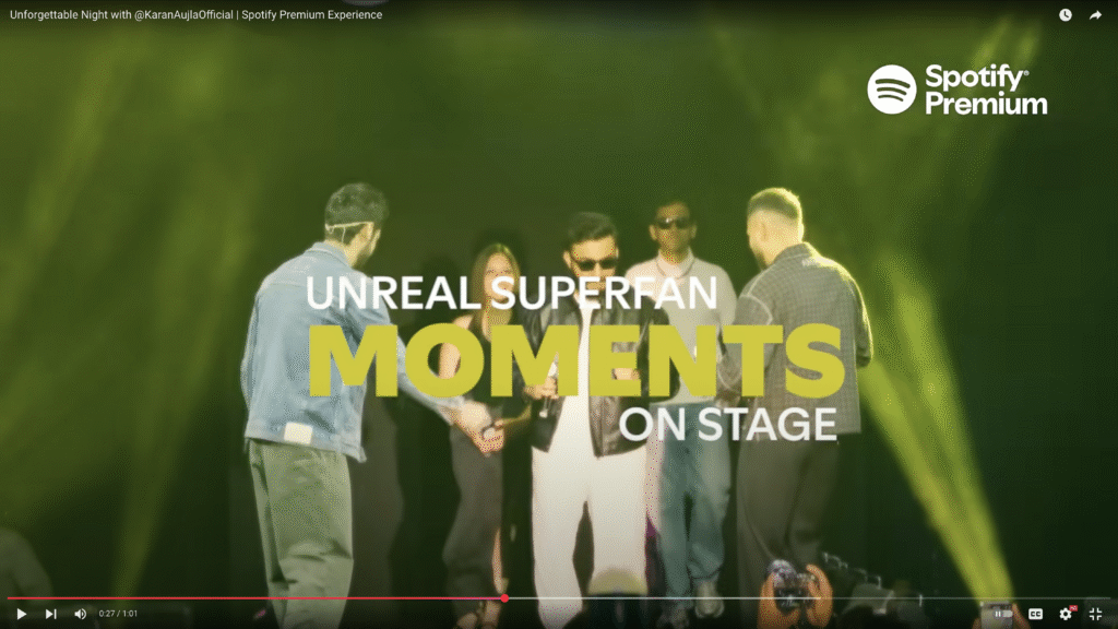Fans join artists on stage during a Spotify Premium concert, sharing an exciting superfan experience under dramatic green lighting with bold event graphics.