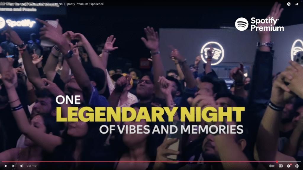 Crowd with raised hands and energetic gestures at a Spotify Premium concert, surrounded by event branding and lively lights.