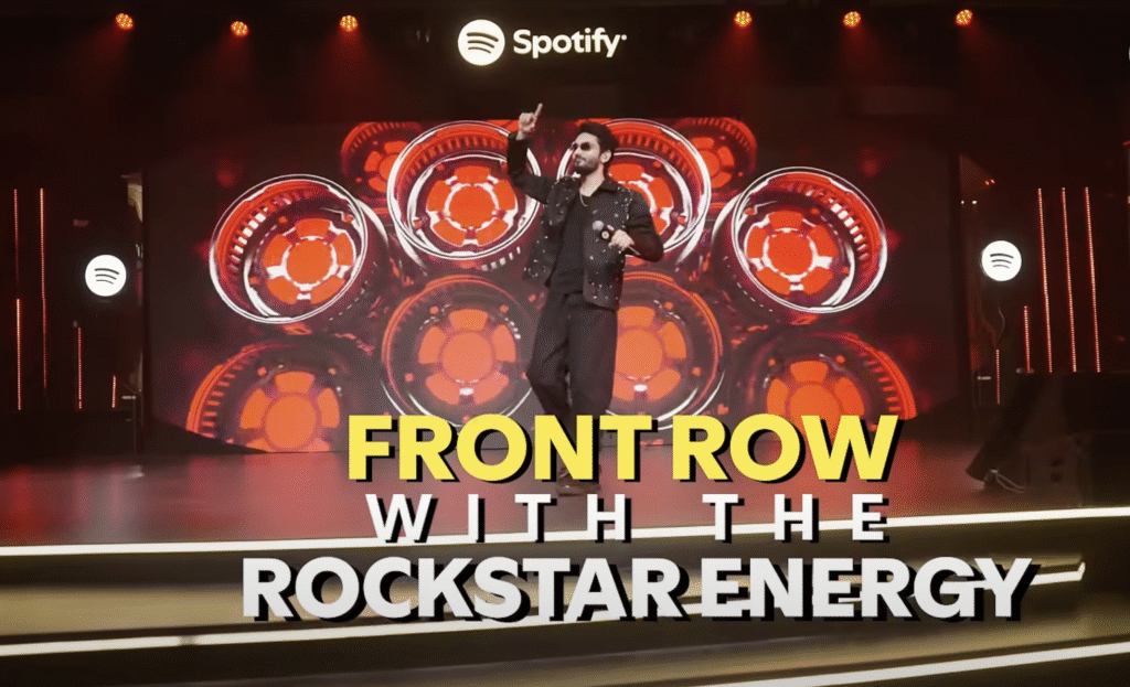 Performer on stage at a Spotify Premium concert delivering a dynamic set, surrounded by vivid lighting and the words "Front Row with the Rockstar Energy" displayed prominently.