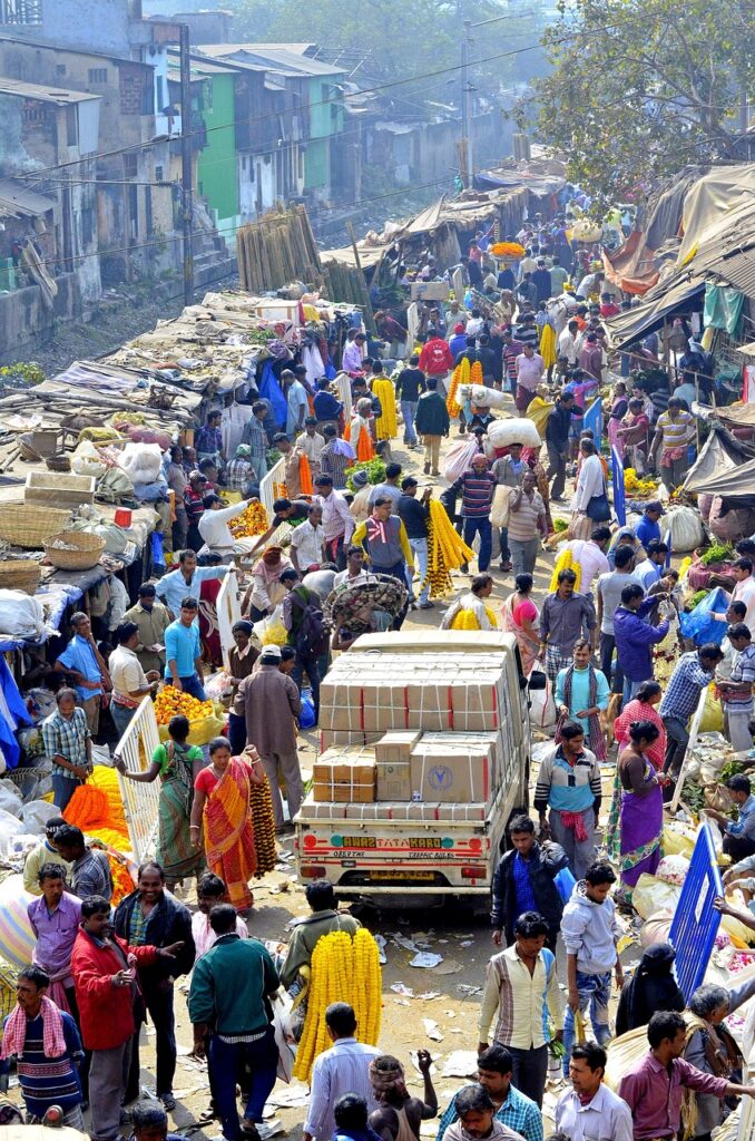 Crowded Indian flower market showing diverse shoppers of all ages and economic backgrounds buying marigolds and traditional items for festivals"