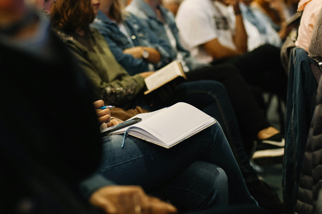 Employees seated at an internal workplace event, with one participant taking notes in a notebook.